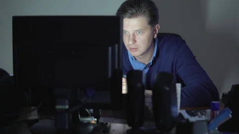 A man is drinking coffee in the office at night at the computer. Stock Footage 82541729