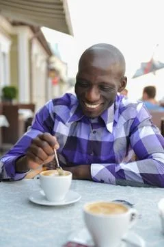 Man drinking coffee out of mug while having a conversation with a friend Stock Photos