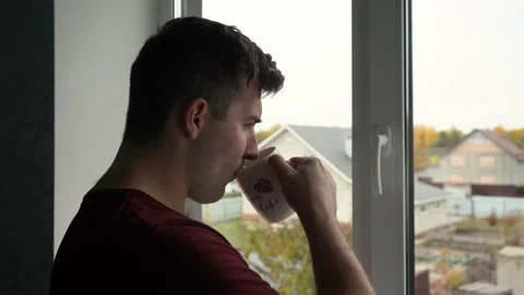 Man drinking coffee standing by the window in the early morning Stock Footage 164591891