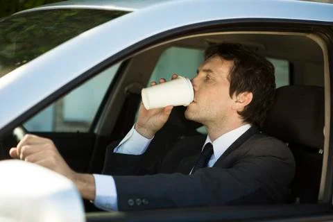 Man drinking coffee while driving car Foto stock