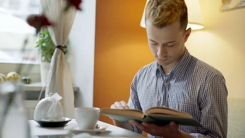 Man drinking coffee while reading interesting book in the cafe Stock-Footage 70685030