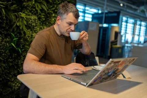 Man drinking coffee while using laptop Stock Photos
