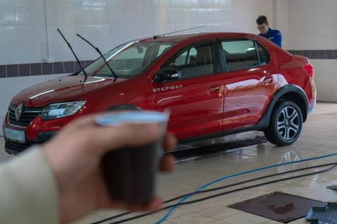 Man drinking coffee while waiting for his car to wash. Car wash. Renault Loga Fotos Stock