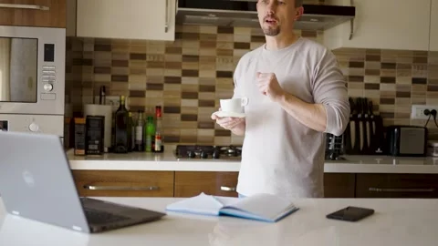 Man Drinking Coffee While Working Remotely in Modern Kitchen. Man standing .. Stock Footage 331971358