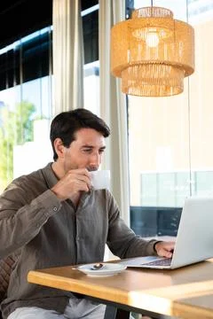 Man drinking coffee working on laptop in cafe Stock Photos