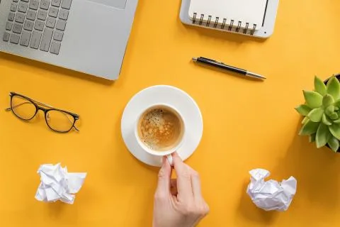 Man drinking coffee on yellow table, top view Stock Photos