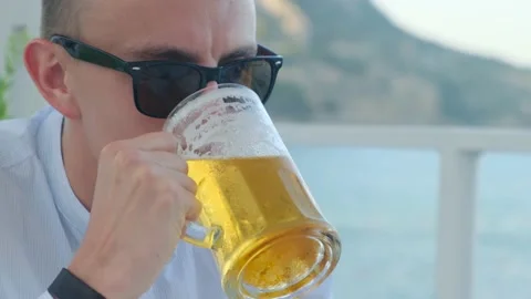 Man drinking cold beer in a cafe by the sea, close-up Stock Footage 158883112