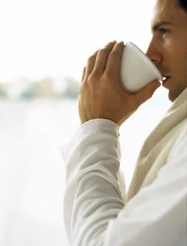 Man drinking cup of coffee, looking away 写真素材