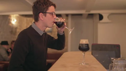 Man Drinking Dark Beer From Stemmed Glass At Bar Counter Stockbeeldmateriaal 344683591