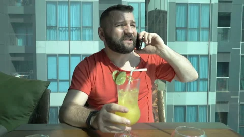 Man drinking fresh beverage in the cafe and chatting on cellphone Stock Footage 88572454