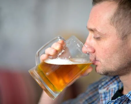 The man is drinking a fresh, cold beer from a large mug Stock Photos