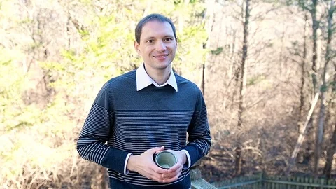 Man drinking green tea outside in garden in slow motion smiling Video stock 107937834