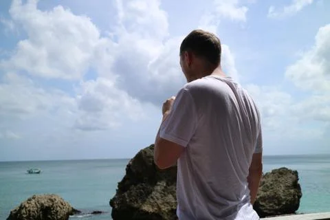 A man drinking on holiday while looking out to sea Stock Photos