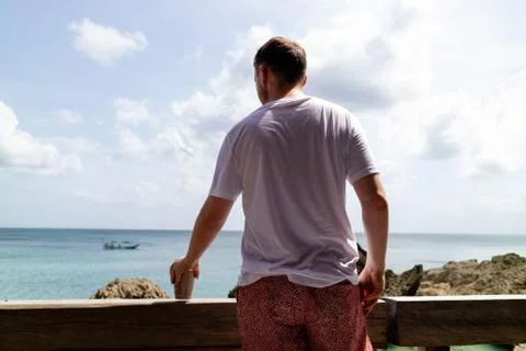 A man drinking on holiday while looking out to sea Stock Photos