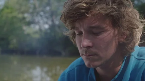 Man is drinking hot beverage by the river bank Video stock 76736539