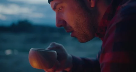 A man is drinking hot tea in nature, campfire, camping, night, close up. Stock Footage