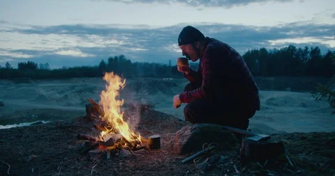 A man is drinking hot tea in nature, campfire, camping, night Stock Footage 128528448