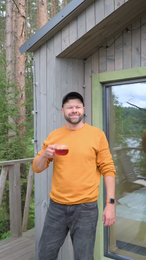 Man drinking hot tea while standing on terrace of wooden house Stock Footage 282382793