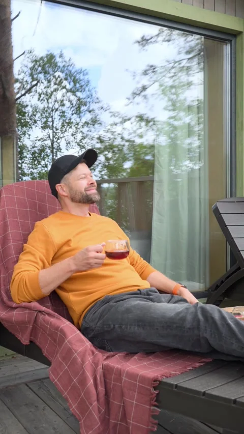 Man drinking hot tea while lying on sun lounger Stock Footage 282382890