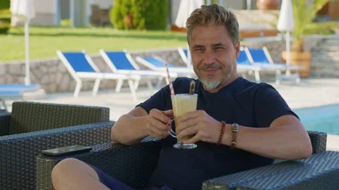 Man drinking ice coffee outdoor on vacation in hotel garden Stock Footage 156080221