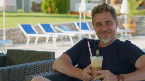 Man drinking ice coffee outdoor on vacation in hotel garden Vidéo 162683538