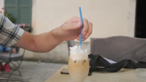 Man drinking iced latte coffee with cream in a glass with a straw in coffee shop Stock Footage 267847496