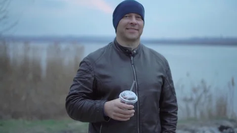 Man Drinking Juice From a Plastic Cup in the Hat and Leather Jacket at Sunset Stock Footage 73904817