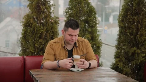 Man drinking latte on the veranda at the table. 库存影片 104023700