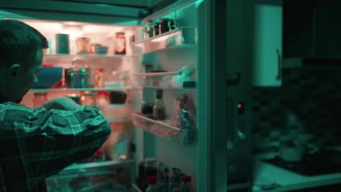 Man drinking milk from carton by open refrigerator at night. A man in a pla.. 스톡 동영상 332055135