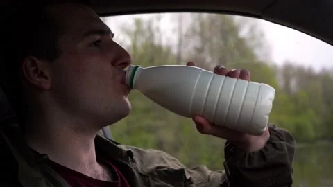 Man drinking milk while sitting in the car 스톡 동영상 162303194