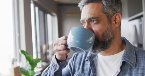 Man drinking mug of coffee and thinking in kitchen alone Video stock 338059773