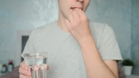 Man drinking a PrEP blue pill with glass of water. HIV prevention using Pre Stock Footage 252040761