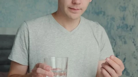 Man drinking a PrEP blue pill with glass of water. HIV prevention using Pre Stock Footage 252040850