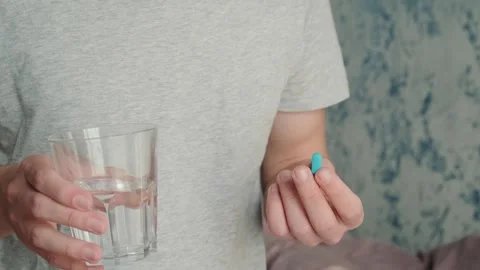 Man drinking a PrEP blue pill with glass of water. HIV prevention using Pre Stock Footage 270570991
