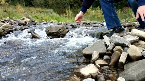A man drinking pure water from wild river and cross it on stones. 動画素材 99341190