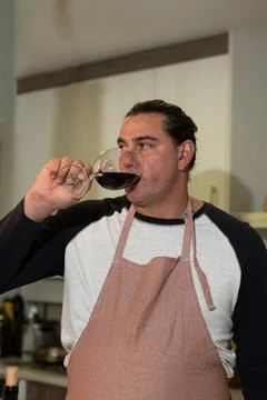 Man drinking red wine, tasting during food preparation 스톡 사진