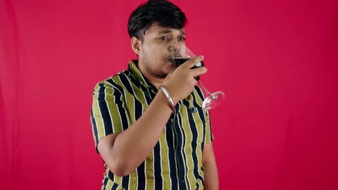 Man drinking smelling red wine and offering to other against a red background Stock Footage 262485441