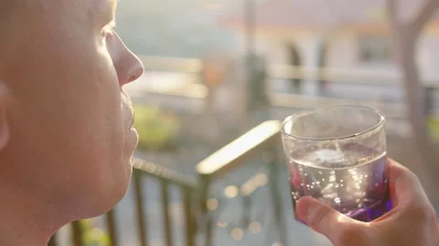 A man drinking a soft drink from a glass, rays of the setting sun Stock Footage 314003456