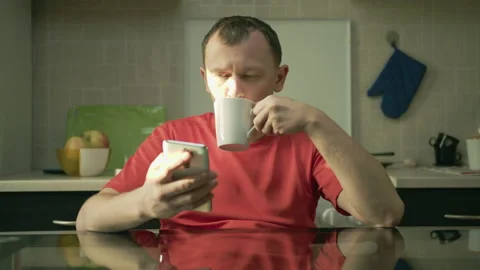 Man drinking tea and reading message in his mobile phone Stock Footage 131030851