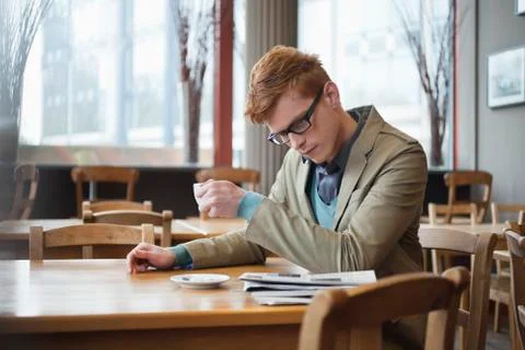 Man drinking tea and reading a newspaper in a restaurant Stock Photos