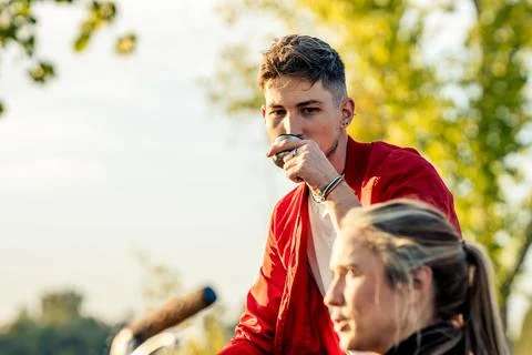 Man drinking tea form a thermo next to t woman in a park Stock Photos