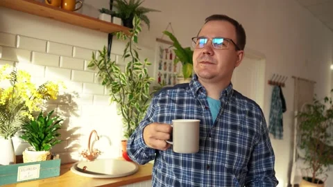 Man drinking tea looking out the window while in the kitchen Stockbeeldmateriaal 166610703