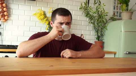 Man drinking tea from a mug sitting at the table in the kitchen Video stock 157585466