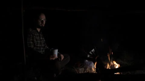 Man drinking tea near campfire at night Stock Footage 63952011