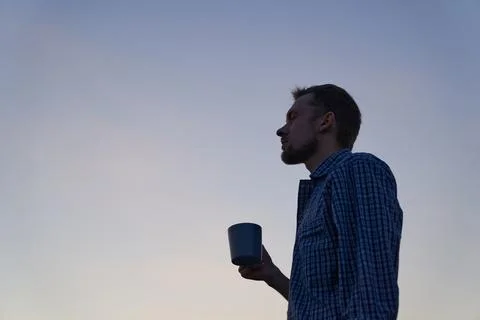 Man drinking tea or coffee outdoor at sunrise in the morning in silhouette Stock-Fotos