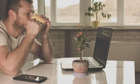 Man drinking tea at a table with a laptop Stock Photos