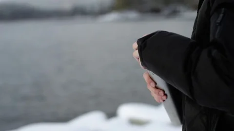 Man drinking tea from a thermos at the view of winter lake Stock-Footage 70808246