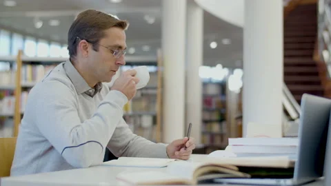 Man drinking tea while studying in library Stock-Footage 232621159