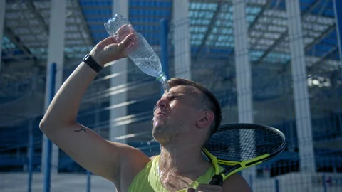 Man Drinking Water and pouring on face After Hard Exercising And Playing Tennis Stock Footage 138525868