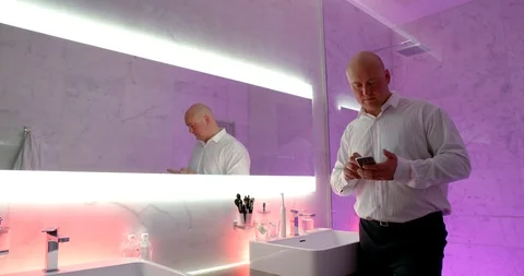 Man is drinking water and reading messages in cell phone in bathroom in hotel Stock Footage 123659092